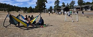 students playing soccer while others recline in hammocks 和 watch