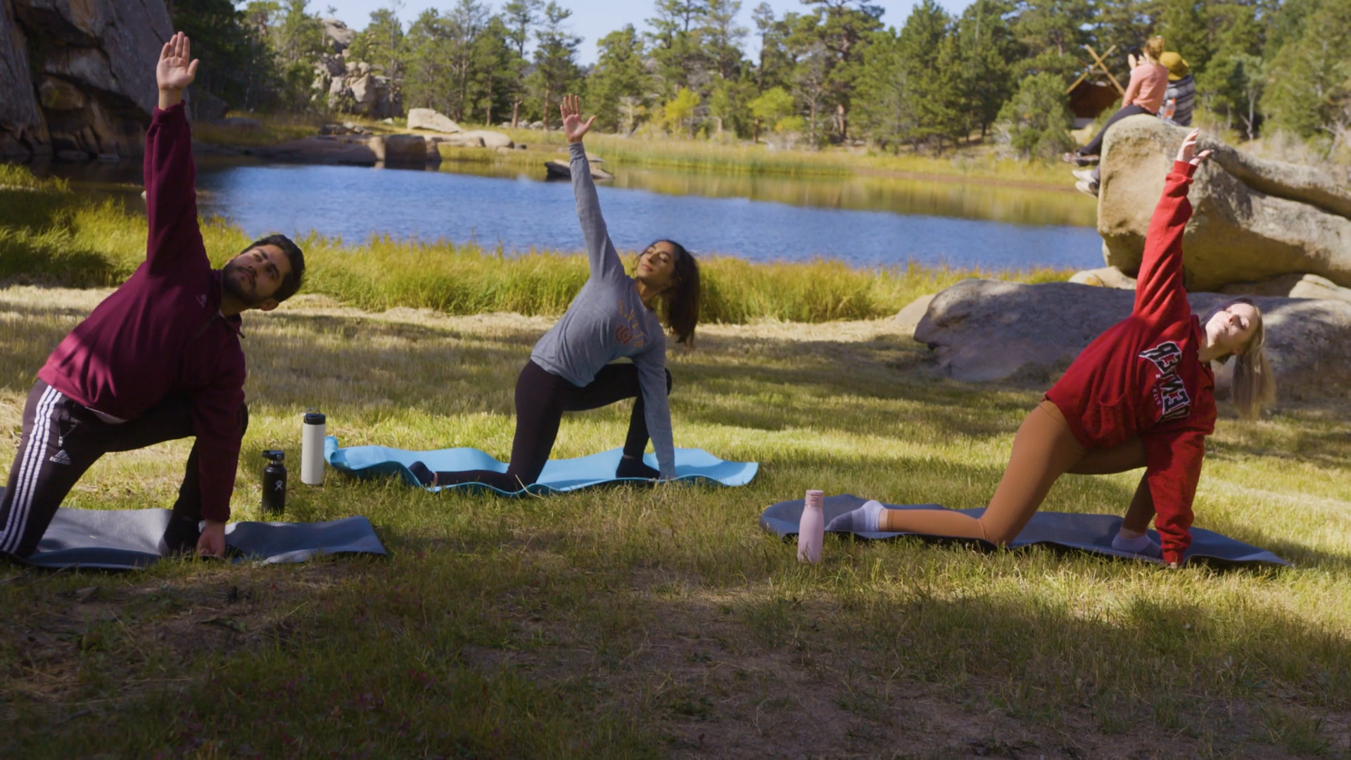 three students doing yoga in meadow